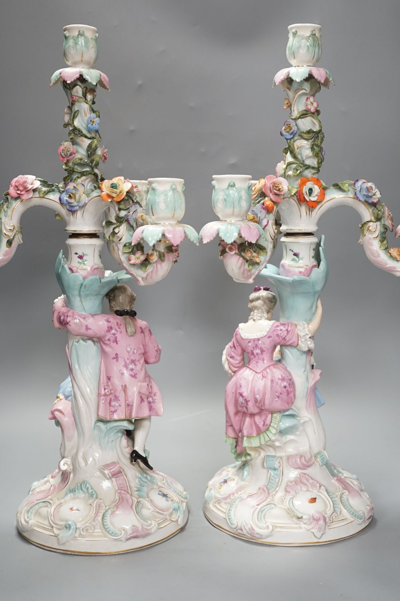 A pair of late 19th century German floral encrusted, figurative porcelain candelabra, 52 cms high.